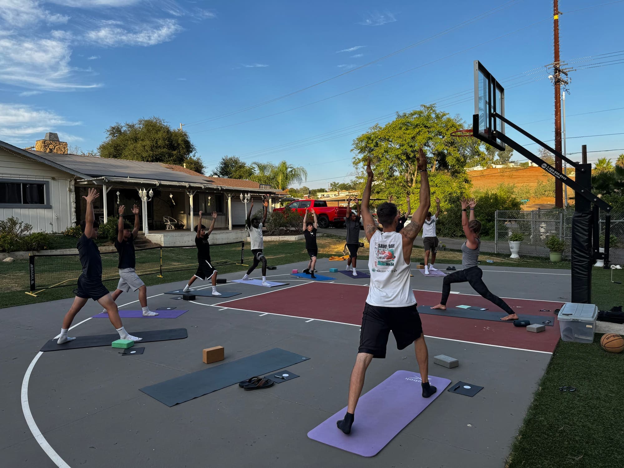 Athletes practicing yoga on an outdoor court during a Mind Body Athletes session