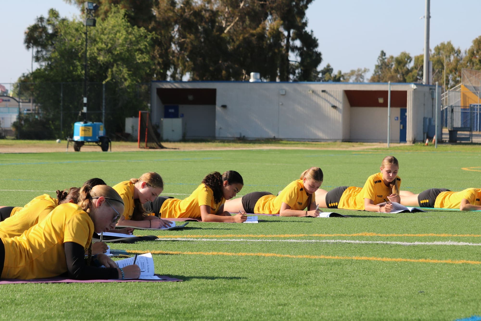 Athletes writing in ACTIVE series workbooks on a turf field