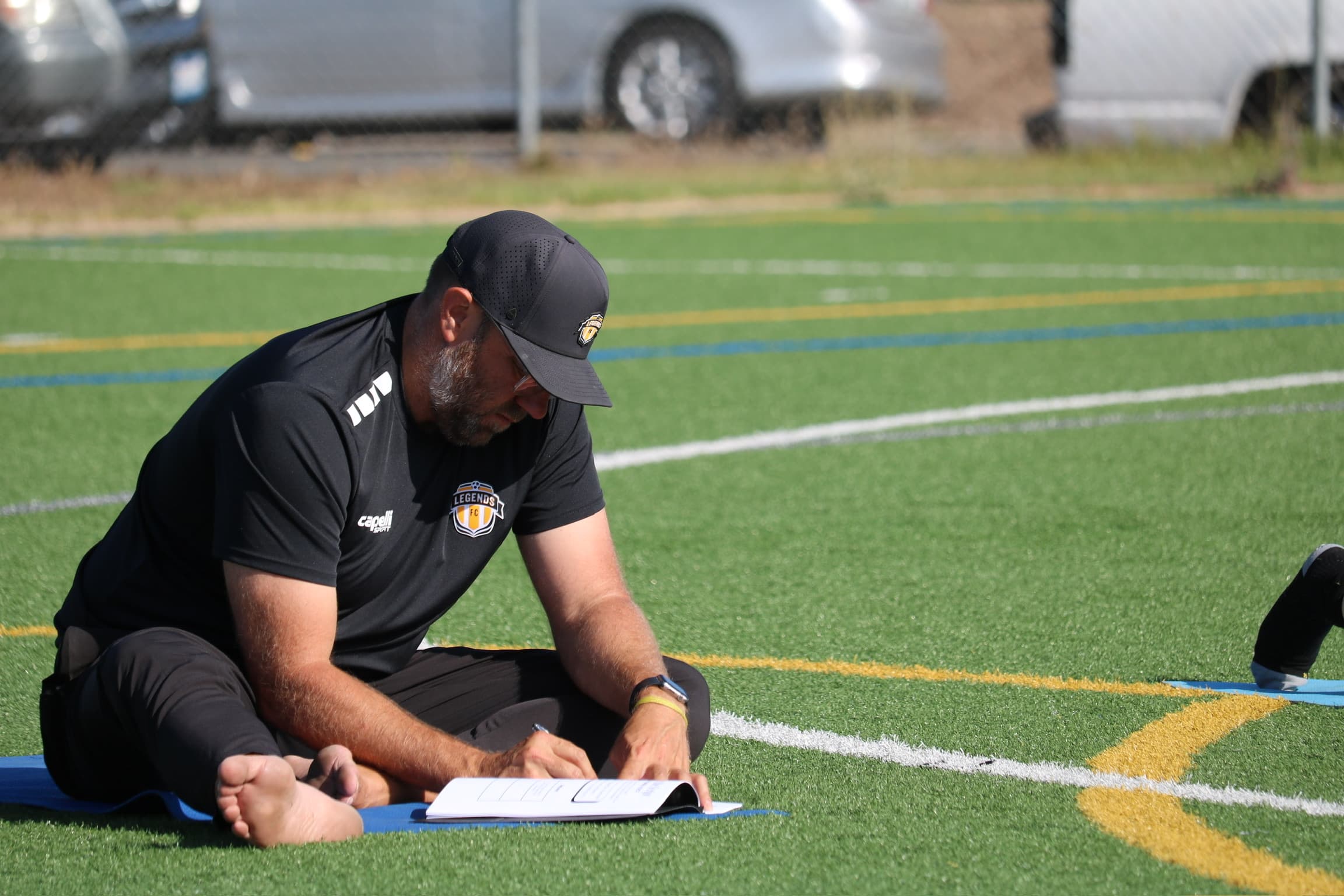 A coach working through the Mind Body Athletes workbook on a turf field