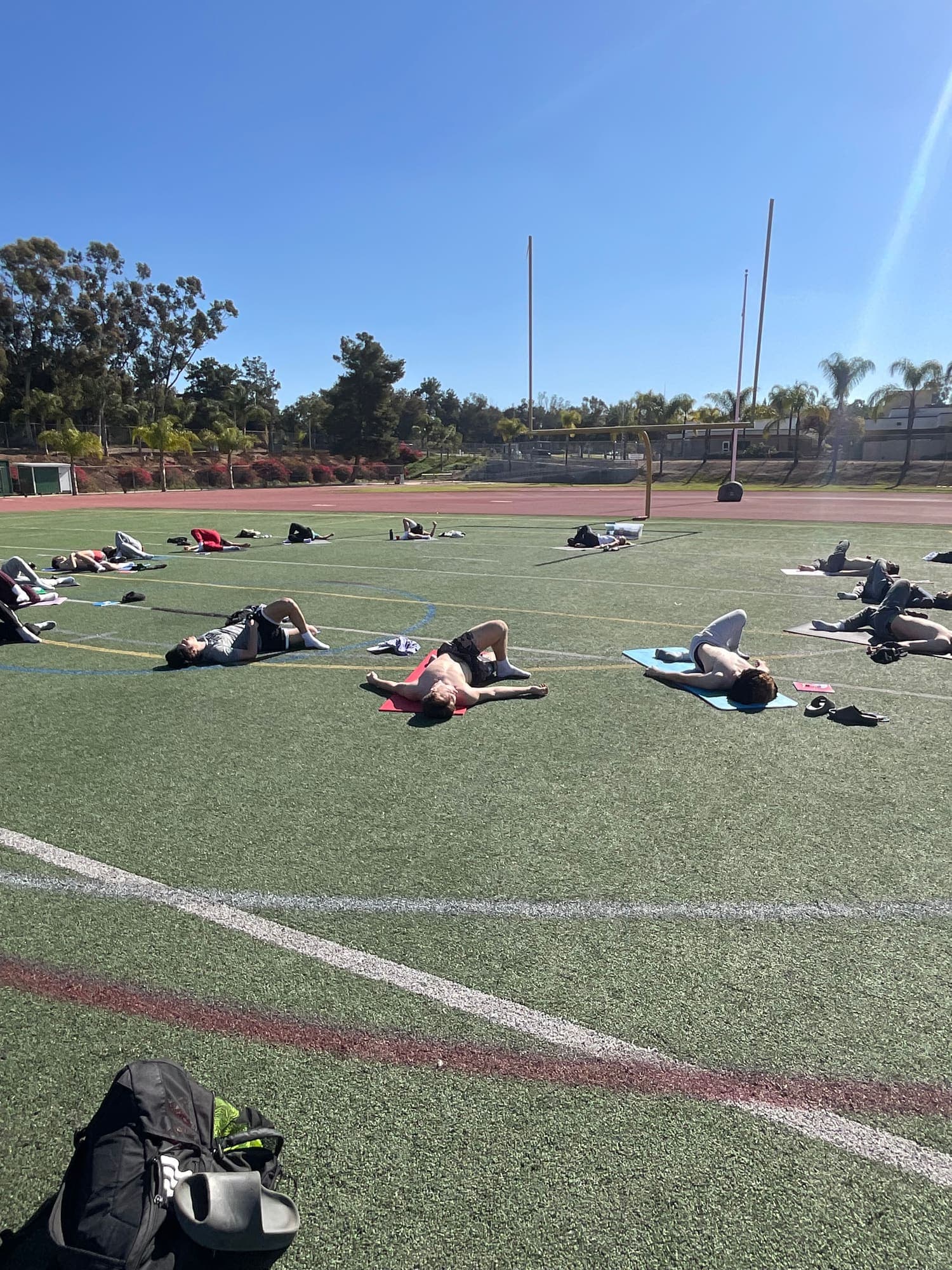 Athletes lying on mats on a turf field during a Mind Body Athletes team workshop