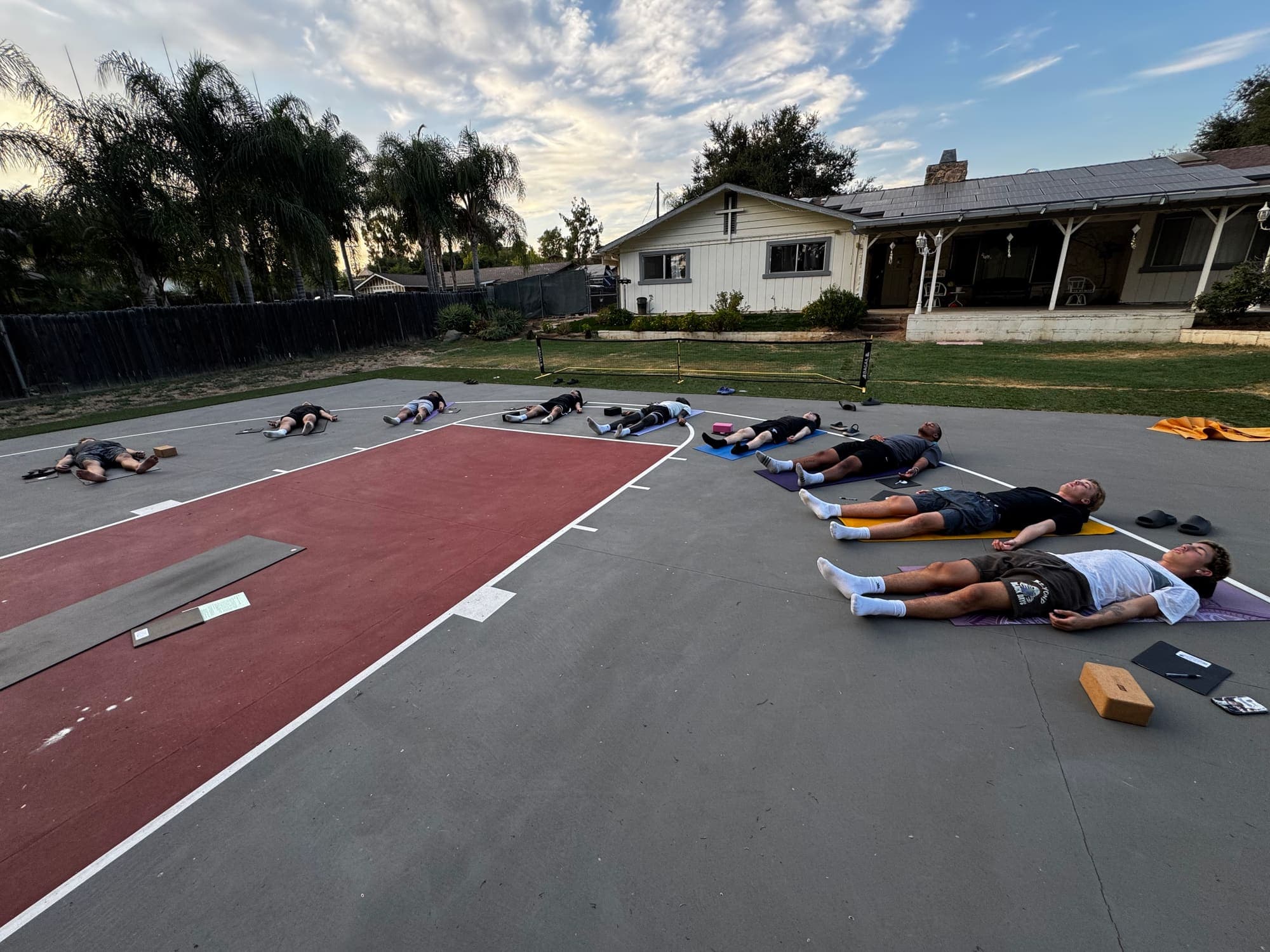 Athletes resting on mats during a licensed team session on an outdoor court